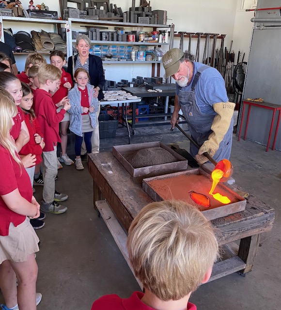 At Studio Waveland last month, students watch as Mitchell Gaudet pours molten glass into molds they created at Coast Episcopal School 