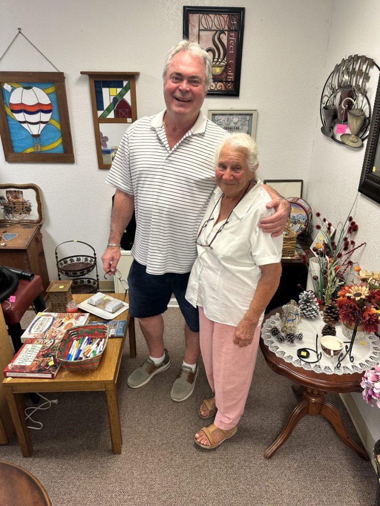 Georgia resident Robert Williams takes time out to pose for a picture with the Family Attic store owner Norma Weeds. Weeds, 91 years old, has made many friends from across the globe working in her Long Beach store. (Photo by Toni Miles)