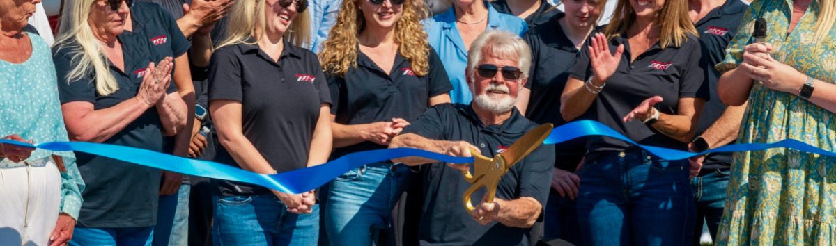 Chuck Ryan (center), owner of Chuck Ryan Cars, cuts the ribbon at the dealership’s recent 50-year anniversary celebration.