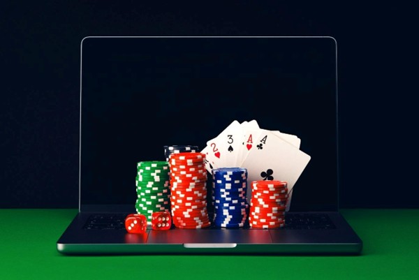 a laptop with casino chips, dice and cards sitting on it