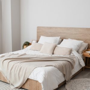A light, airy bedroom with a full-size bed placed in the center of two matching night stands. There is a window on the left.