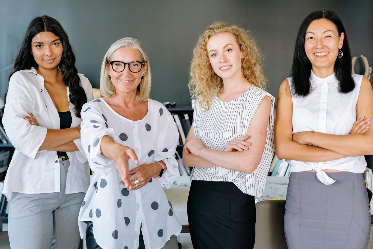 business women looking at the camera and one reaching out for a hand shake