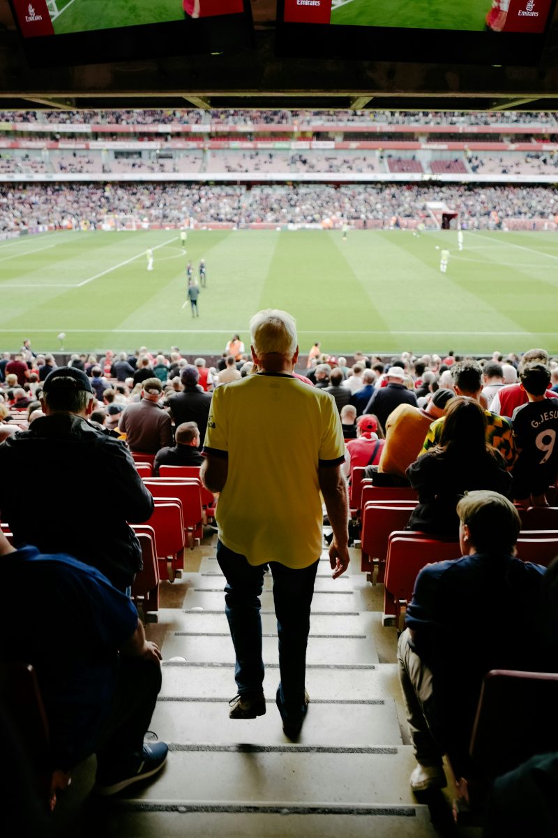older man walking down the stadium stairs at a football stadium