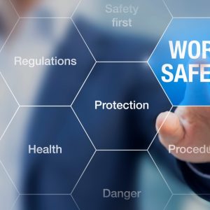 A businessman reaches and presses an octagon labeled "Work Safety" on a digital grid. Other octagons feature related words.