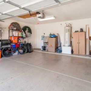 An organized garage features shelving units with bins and boxes, a bicycle, a lawn mower, and a tall cabinet.