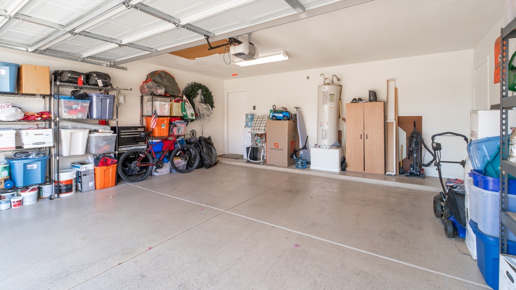 An organized garage features shelving units with bins and boxes, a bicycle, a lawn mower, and a tall cabinet.