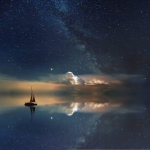 boat sailing in the ocean with milky way galaxy in the night sky