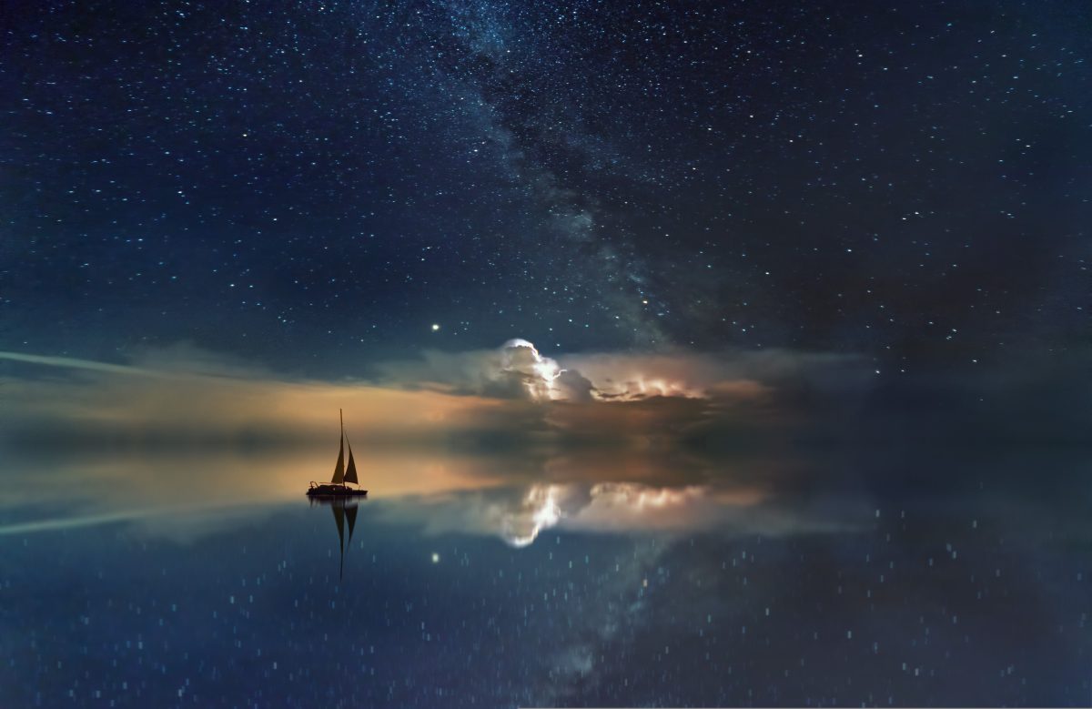 boat sailing in the ocean with milky way galaxy in the night sky
