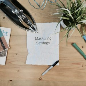 marketing strategy written on paper with iron plant and books on table