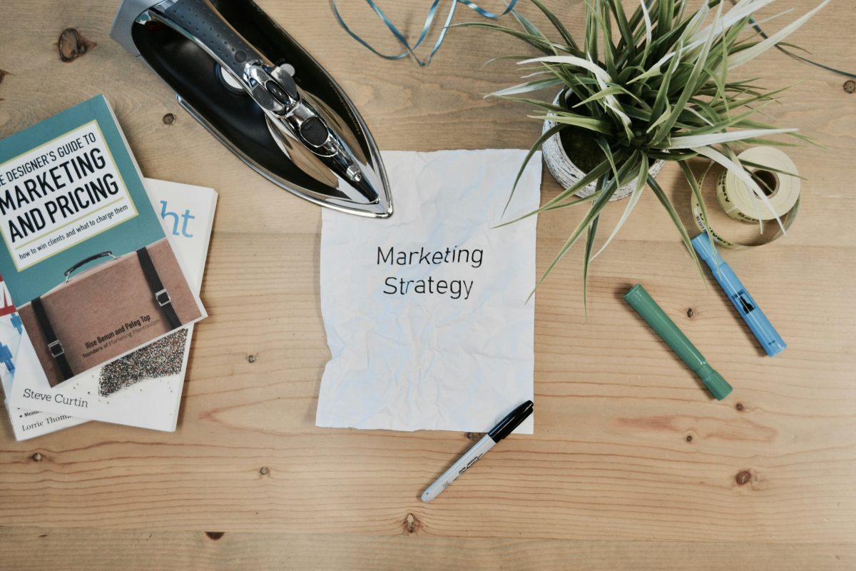 marketing strategy written on paper with iron plant and books on table