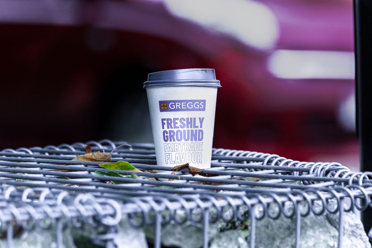greggs coffee cup on outdoor metal bench
