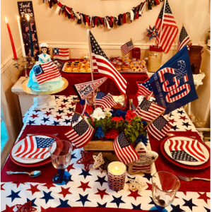 The Fourth of July tablescape of my dreams, Courtesy of red, white and blue linens and dishes; festive centerpiece of flowers, flags and a red lantern and holding court on the left, foreground, homemade Betsy Ross cake. (Photo by Kara Kimbrough)