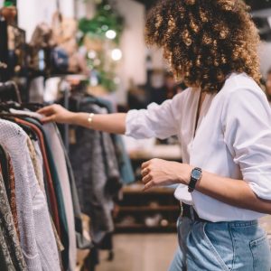A woman browsing a clothing rack in a boutique store among curated fashion displays and accessories.