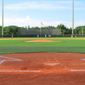 Members of two different baseball teams are warming up in the outfield of a well-maintained baseball field.