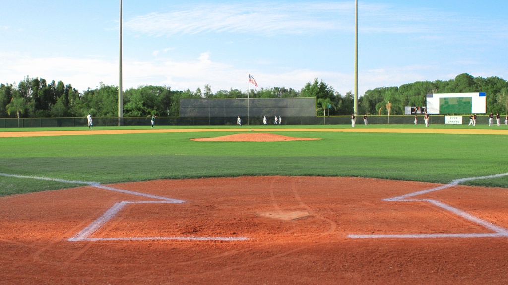 Members of two different baseball teams are warming up in the outfield of a well-maintained baseball field.