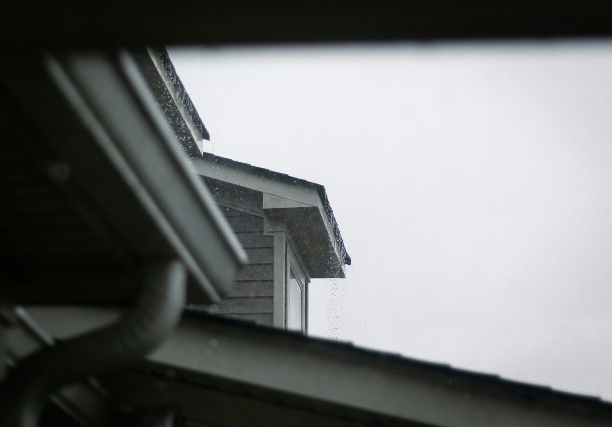 a house roof and gutter system against a grey rainy sky