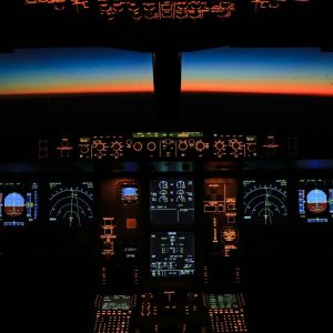 An airplane cockpit at night with glowing instrument panels and a horizon line
