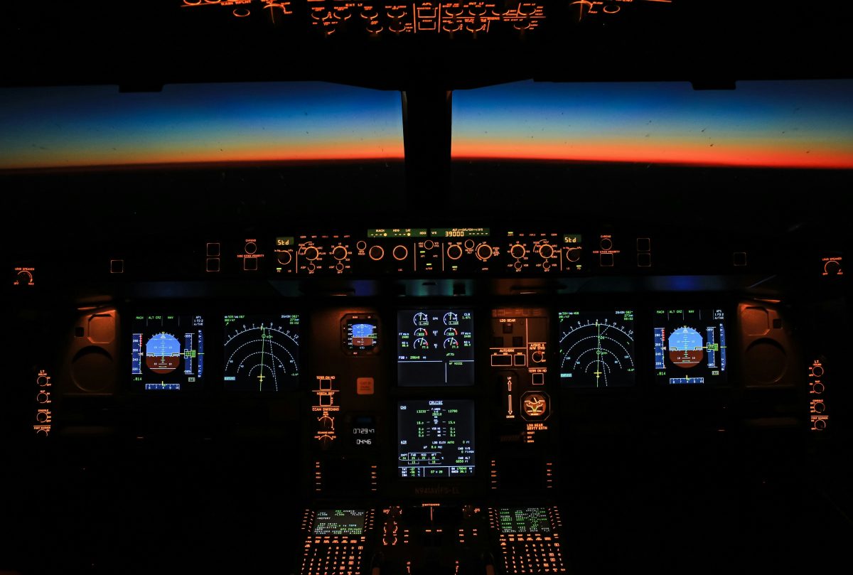 An airplane cockpit at night with glowing instrument panels and a horizon line