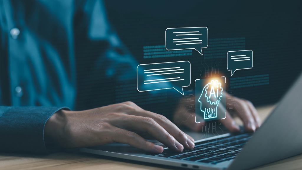 A person typing on a laptop, with a glowing AI head and speech-bubble graphics appearing above the keyboard.