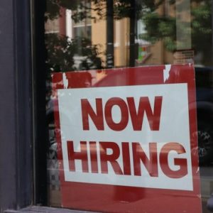 A now-hiring sign in a storefront window. Photo: Nathan Sack / Unsplash