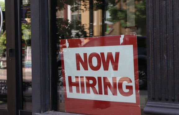 A now-hiring sign in a storefront window. Photo: Nathan Sack / Unsplash