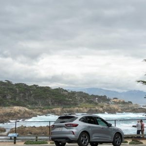 Silver suv parked by a cloudy coastal landscape