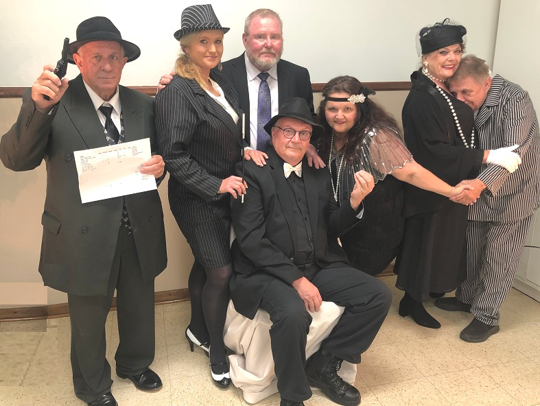 Father Martin J. Gillespie (pictured center, sitting down), also known as "Father G," played the role of Godfather Don Martini Giuseppe during the 2022 Murder Mafia Mystery Dinner, a fundraiser hosted by MS SOFIA (the Mississippi Society of Italian Americans), which included a number of Catholic parishioners from the area. He passed away on Friday, September 5, leaving a lasting legacy.